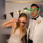 newly married wedding couple, bride in beautiful wedding dress, bridegroom in white dinner jacket, enjoying party and taking pictures at photo booth in the evening